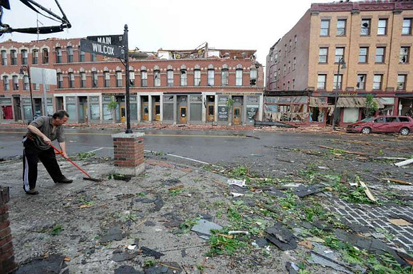 Anthony Ricco sweep up debris after a reported tornado struck downtown Springfield, Mass.
