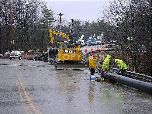 Workers inspect the collapse of a culvert on Route 119 in Littleton.