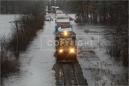 Spectacle Pond flooded Monday after the culvert at Route 119 collapsed. A train made slow progress on flooded tracks next to the pond.