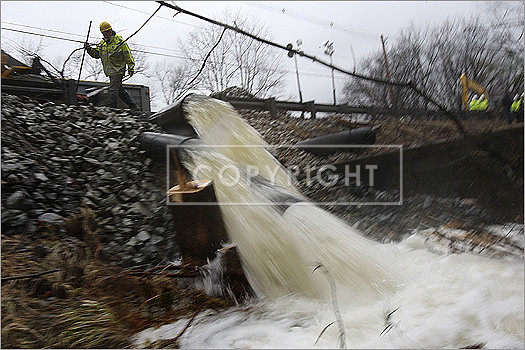A crew working along Route 119 raced to pump water out of the pond to avoid further flooding.