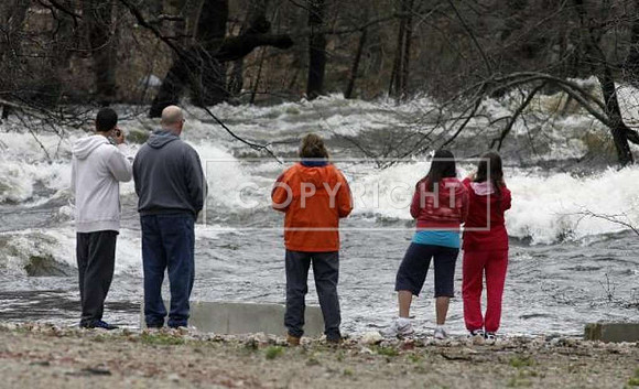 Residents watch the rising Pawtuxet River in West Warwick, R.I.