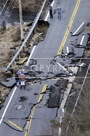 People examine a washed-out road along the Wood River in Hopkinton, R.I.