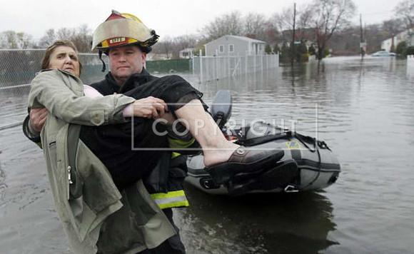 Lt. Brian Poland carries Phyllis Rego to dry land while helping rescue her from a flooded neighborhood in East Providence, R.I.