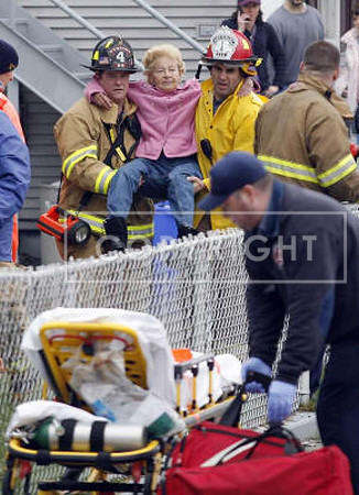 West Warwick, R.I., firefighters evacuate an elderly resident from her flooded house near the Pawtuxet River.