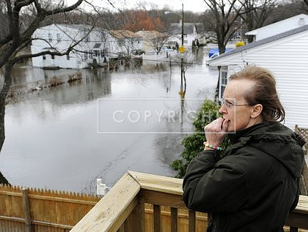 Beverly Van Slyke, of Cranston, R.I., surveys a flooded street from a neighbor's deck in Cranston, R.I.