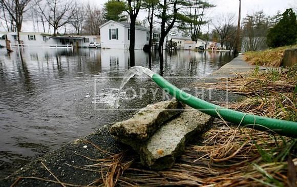 Water from a flooded basement flows out of a hose on Westchester Street in Salem,