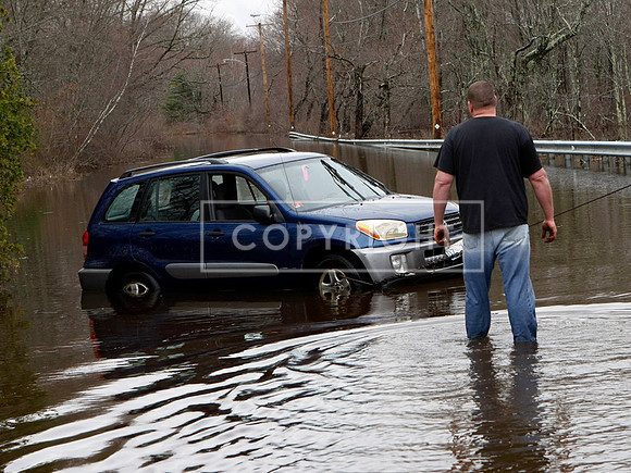 A tow truck operator checks on a car he is pulling out of a flooded road in Exeter, R.I
